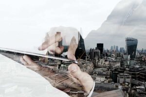 Banner image for benefits of managed IT services for businesses , showing a city and a person using a tablet.
