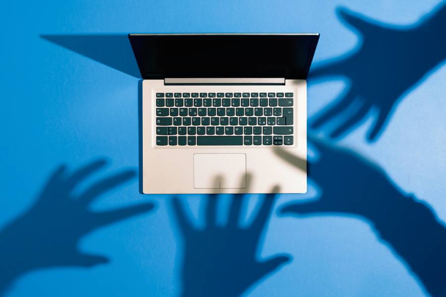 Hand shadows reaching for a laptop