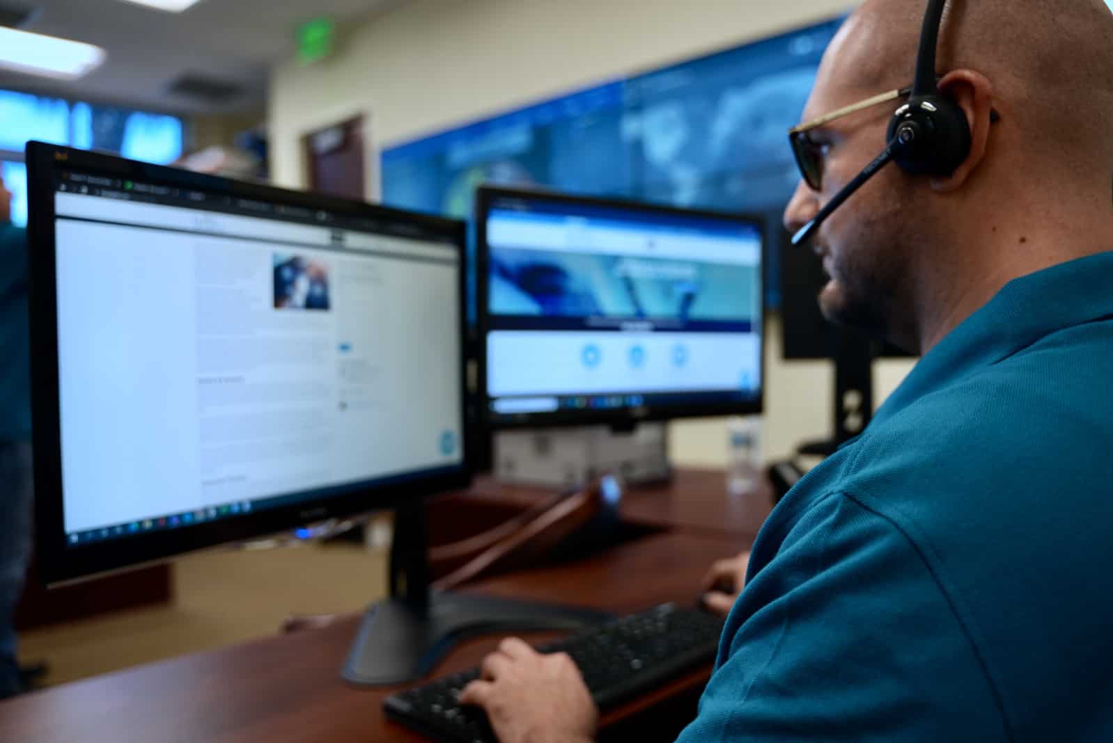 A Blue Light IT team member at their desk looking at two monitors to provide IT services.