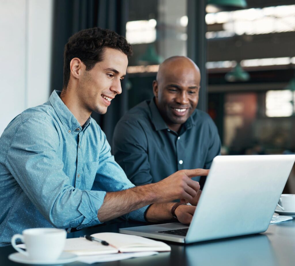 An IT consultant working with a client on a laptop.